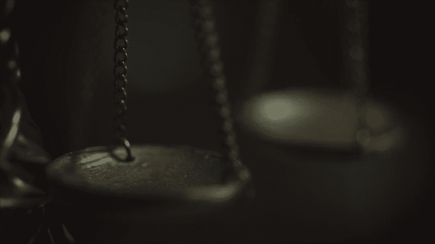 Close-up of a hanging balance scale in dim light.